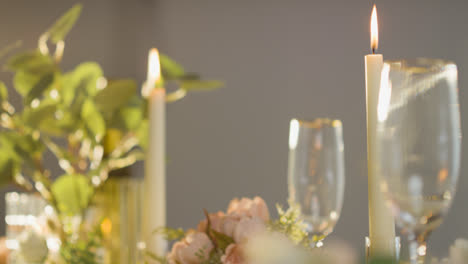 Nahaufnahme-Von-Kerzen,-Blumen-Und-Gläsern-Auf-Dem-Tisch,-Der-Für-Das-Essen-Bei-Der-Hochzeitsfeier-Im-Restaurant-Gedeckt-Ist
